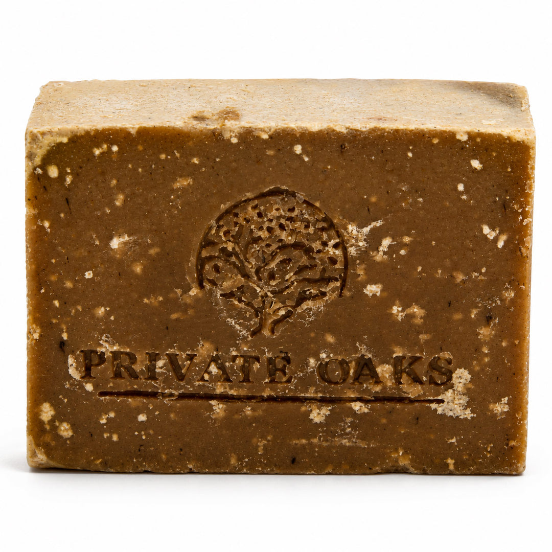 A rectangular bar of brown soap with visible speckles and an embossed tree logo and the words 'PRIVATE OAKS' on the front, photographed on a white background.
