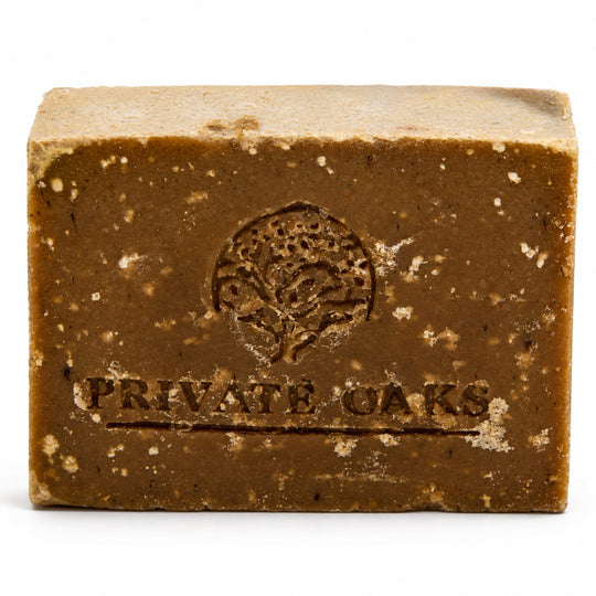 A rectangular bar of brown soap with visible speckles and an embossed tree logo and the words 'PRIVATE OAKS' on the front, photographed on a white background.
