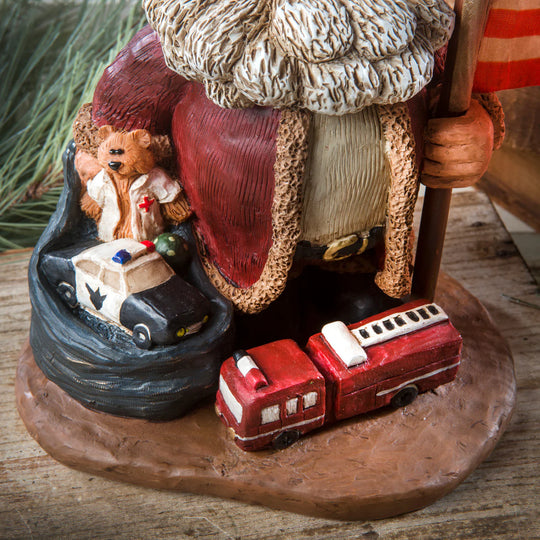 Decorative figurine with teddy bear, ambulance, and fire truck on a wooden base