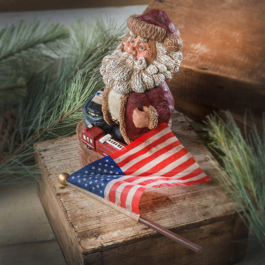Santa Claus figurine with an American flag on a rustic wooden platform.