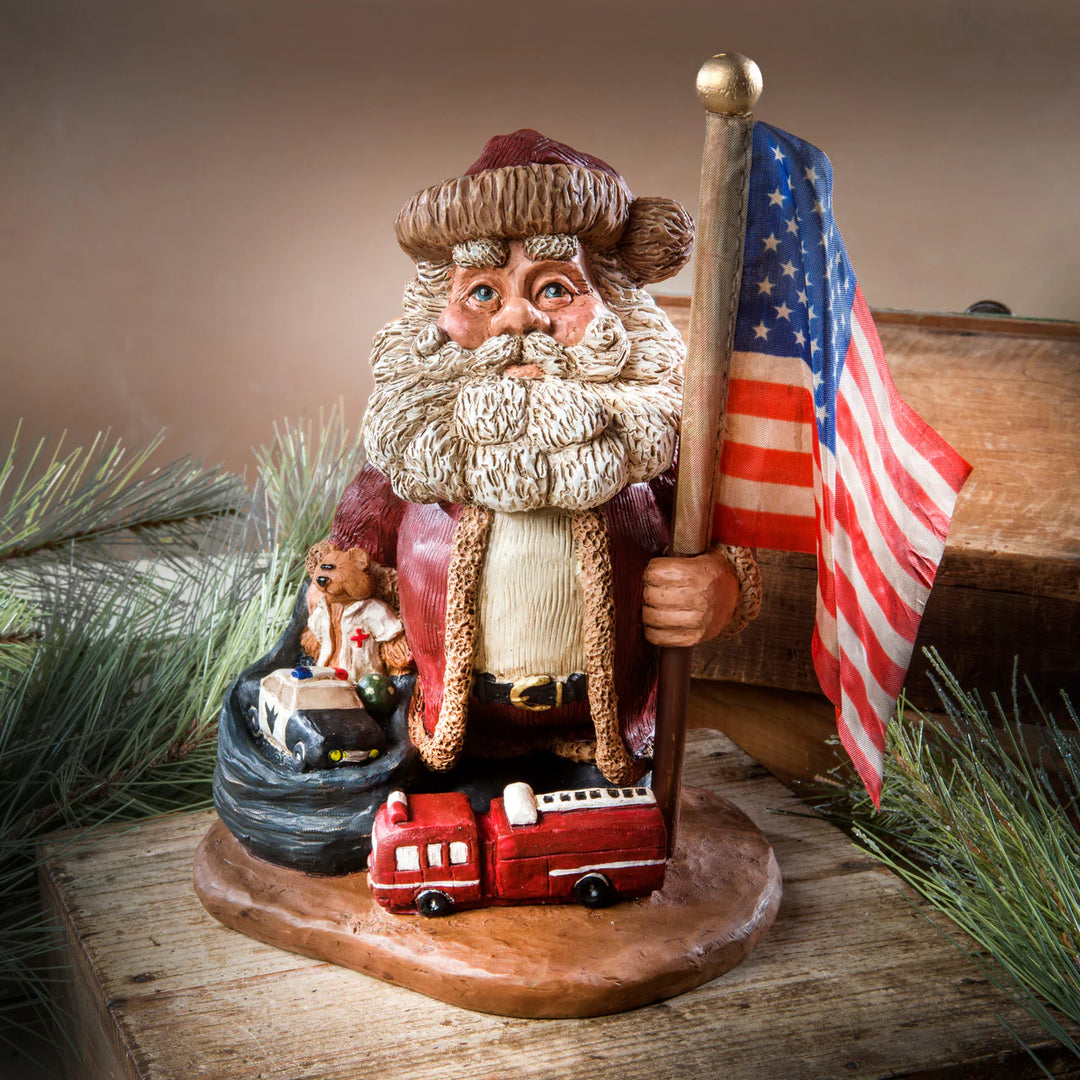 Decorative figurine of Santa with a red flag and small fire truck on a wooden base.