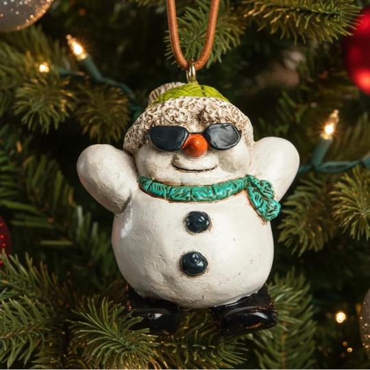 Short fat snowman wearing sunglasses, bright green stocking hat and turquoise scarf on black skis, shown on a Christmas tree