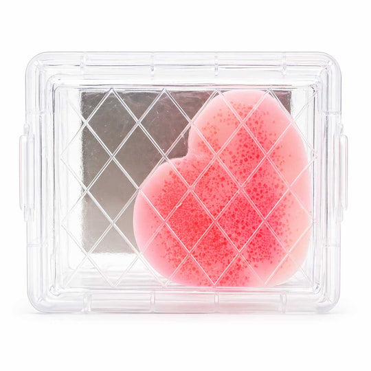 Pink heart-shaped sponge in a clear plastic container on a white background
