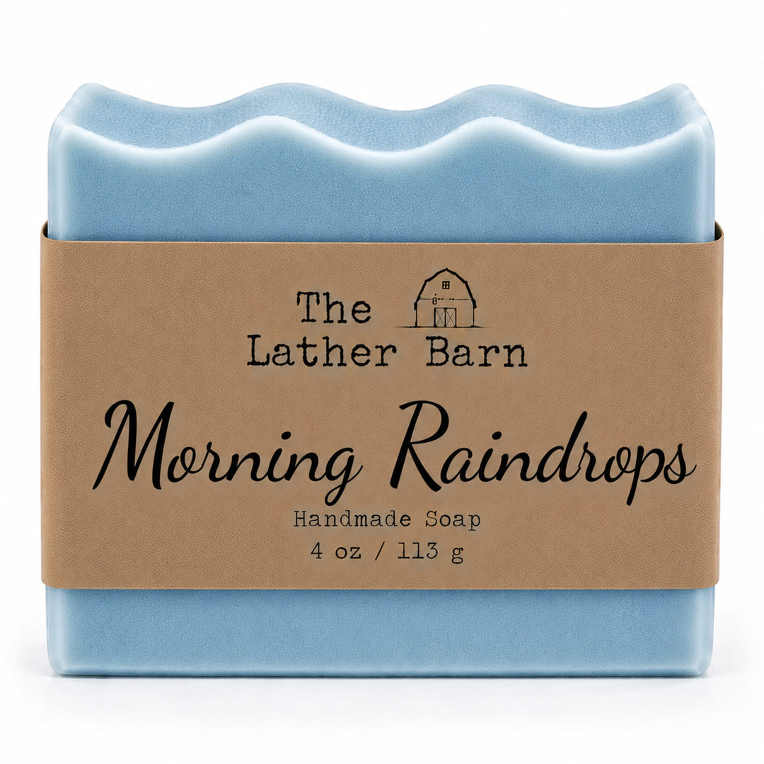 A bar of handmade soap wrapped in a brown kraft paper band. The soap has a wavy top edge and is a light sky blue color.