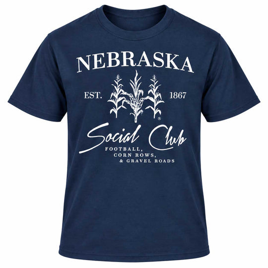 A navy blue short-sleeve t-shirt with a white graphic print on the front. The graphic features the word 'NEBRASKA' in arched capital letters above three white corn illustrations, with 'EST.