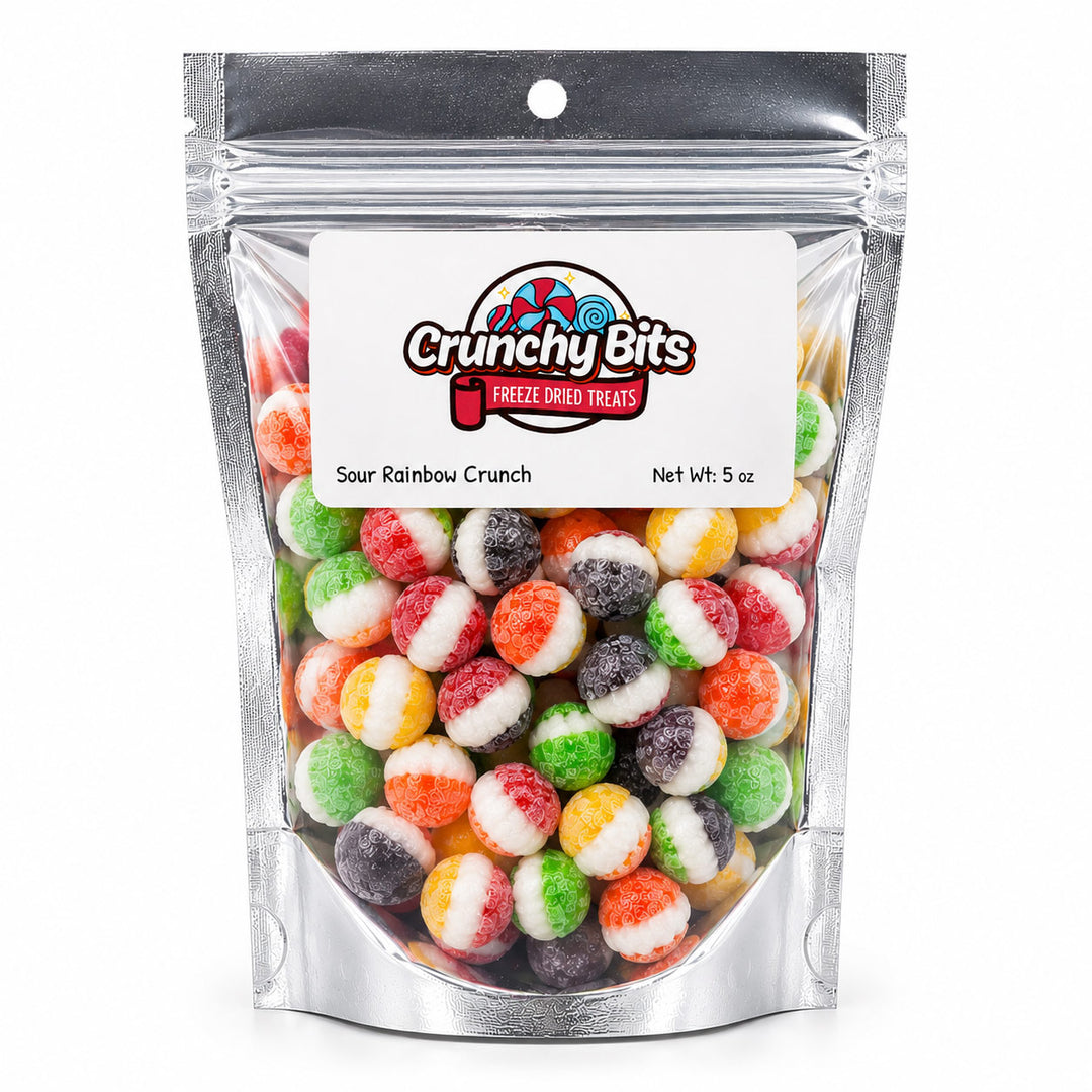 A 5 oz stand-up pouch of Crunchy Bits Sour Rainbow Crunch freeze dried treats, filled with colorful round candies in red, orange, yellow, green, white, and purple, on a white background.