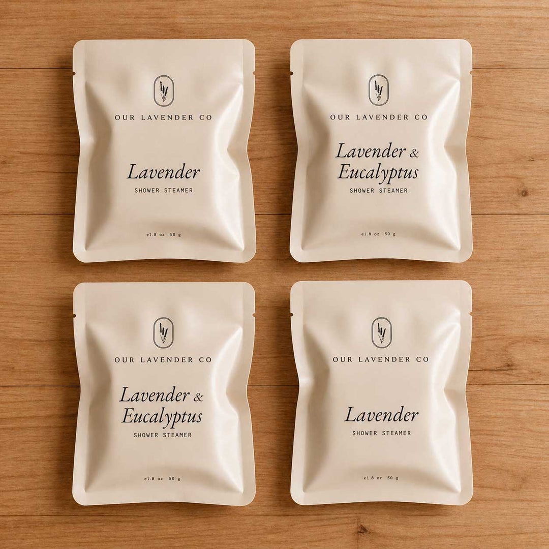 Four packages of Lavender & Eucalyptus shower steamers from Our Lavender Co on a wooden surface.