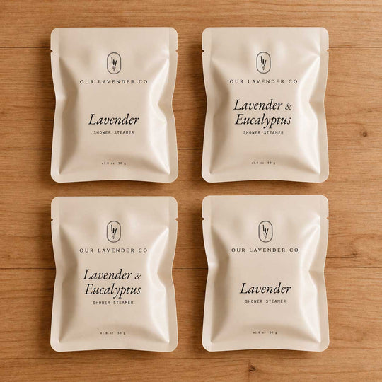 Four packages of Lavender & Eucalyptus shower steamers from Our Lavender Co on a wooden surface.