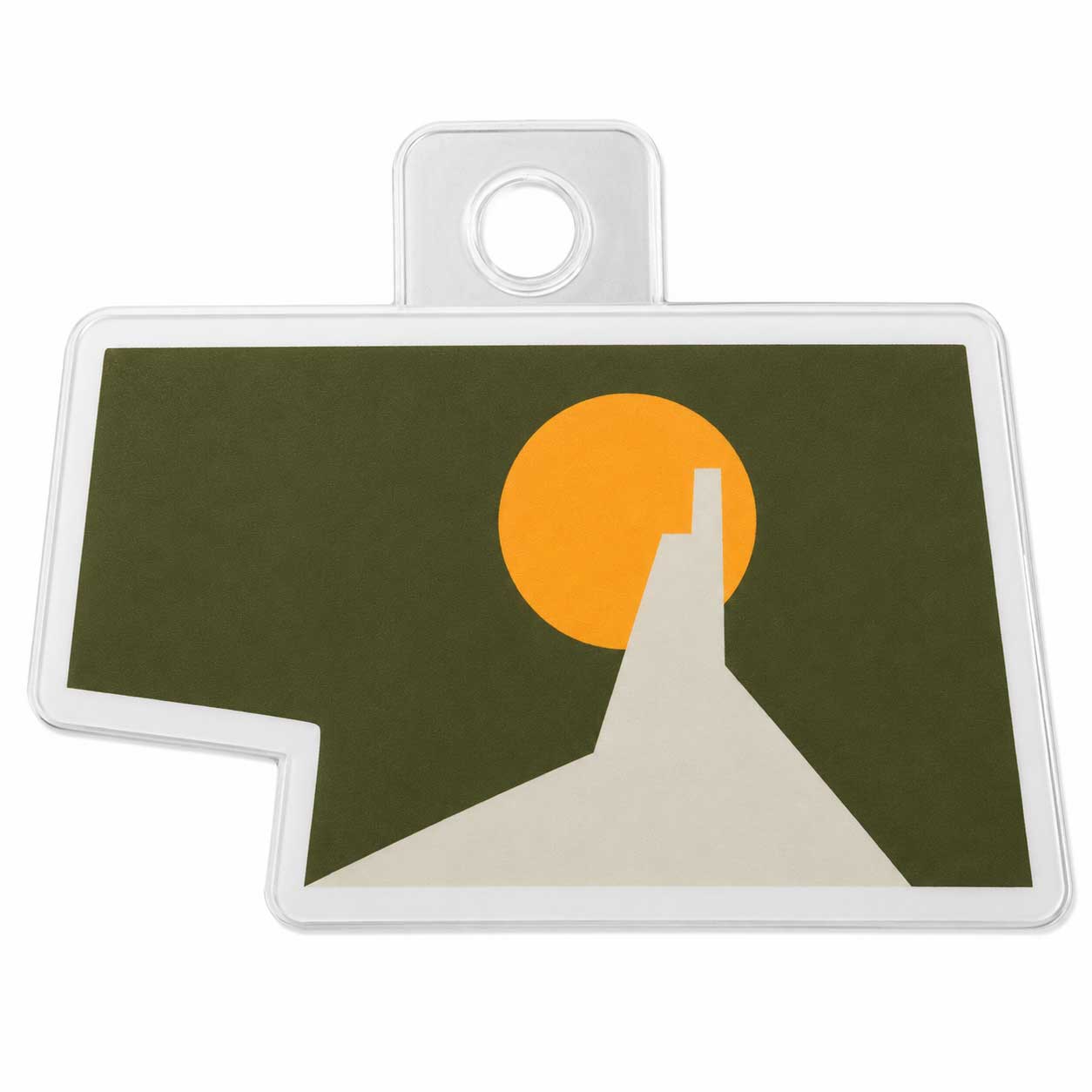 A die-cut acrylic keychain or tag with a modern minimalist desert landscape design, featuring an orange sun, beige rock spire, and dark olive green background, set against a plain white studio background.