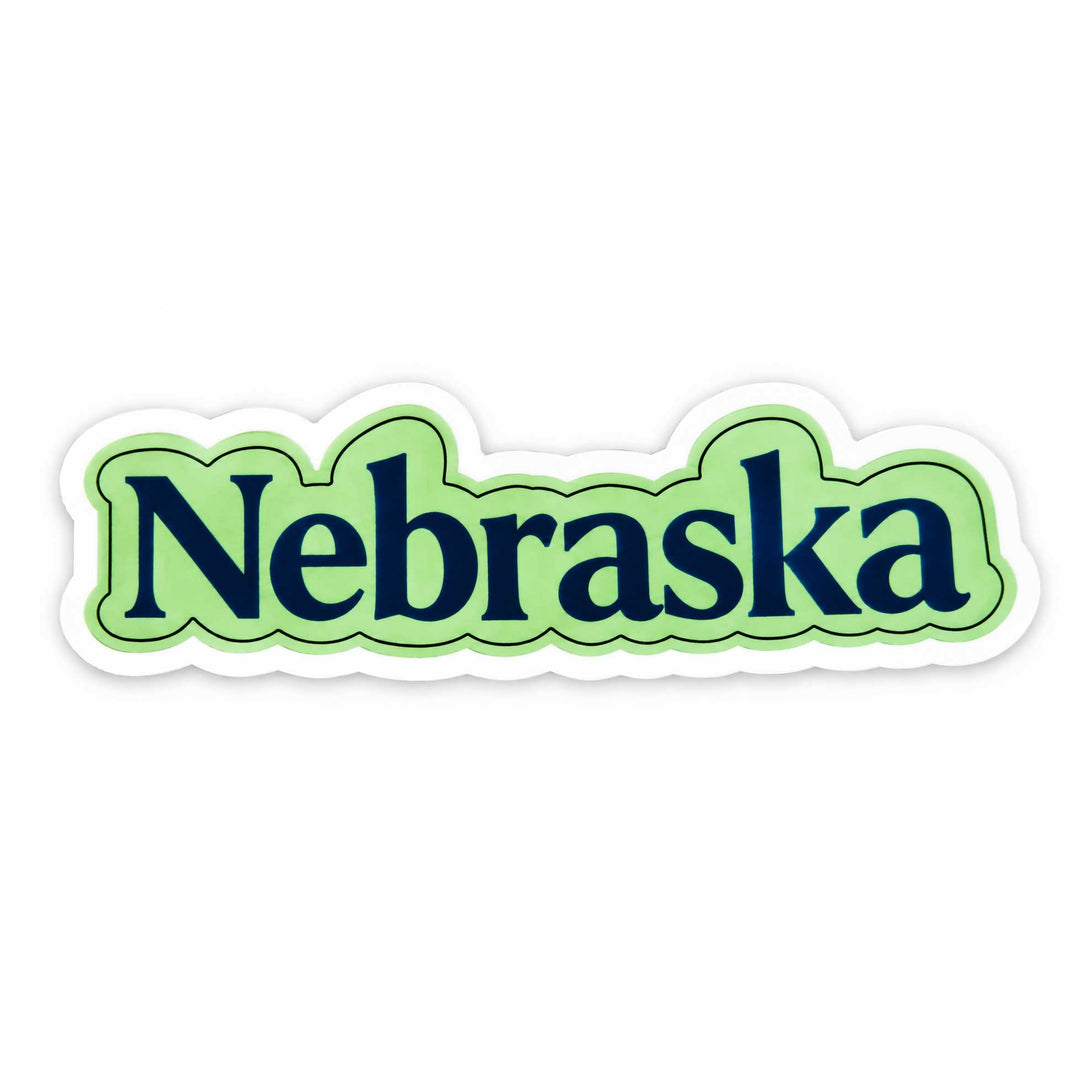 A die-cut sticker featuring the word 'Nebraska' in dark navy blue serif lettering, outlined in green and light green wavy borders, with a white contour cutout on a plain white background.