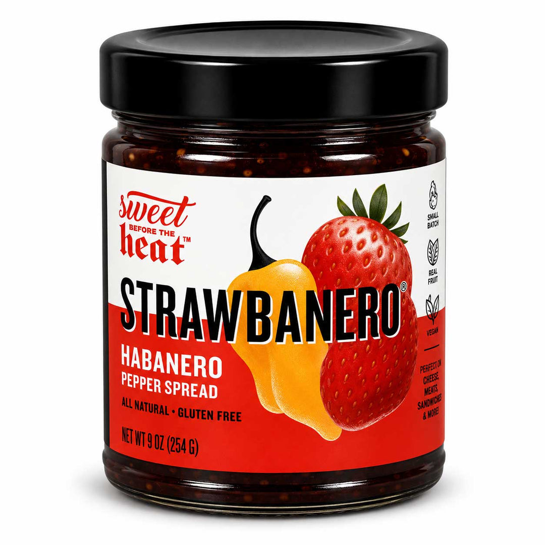 A jar of Sweet Heat Strawberry Habanero Pepper Spread on a white background. The product features a black lid, a clear glass jar showing the dark red pepper spread inside, and a label with illustrations of a yellow habanero pepper and a red strawberry.