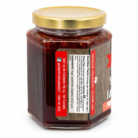 Jar of strawberry jam with a gold lid on a white background
