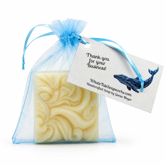 Handcrafted soap in a blue drawstring bag with a business card attached on a white background