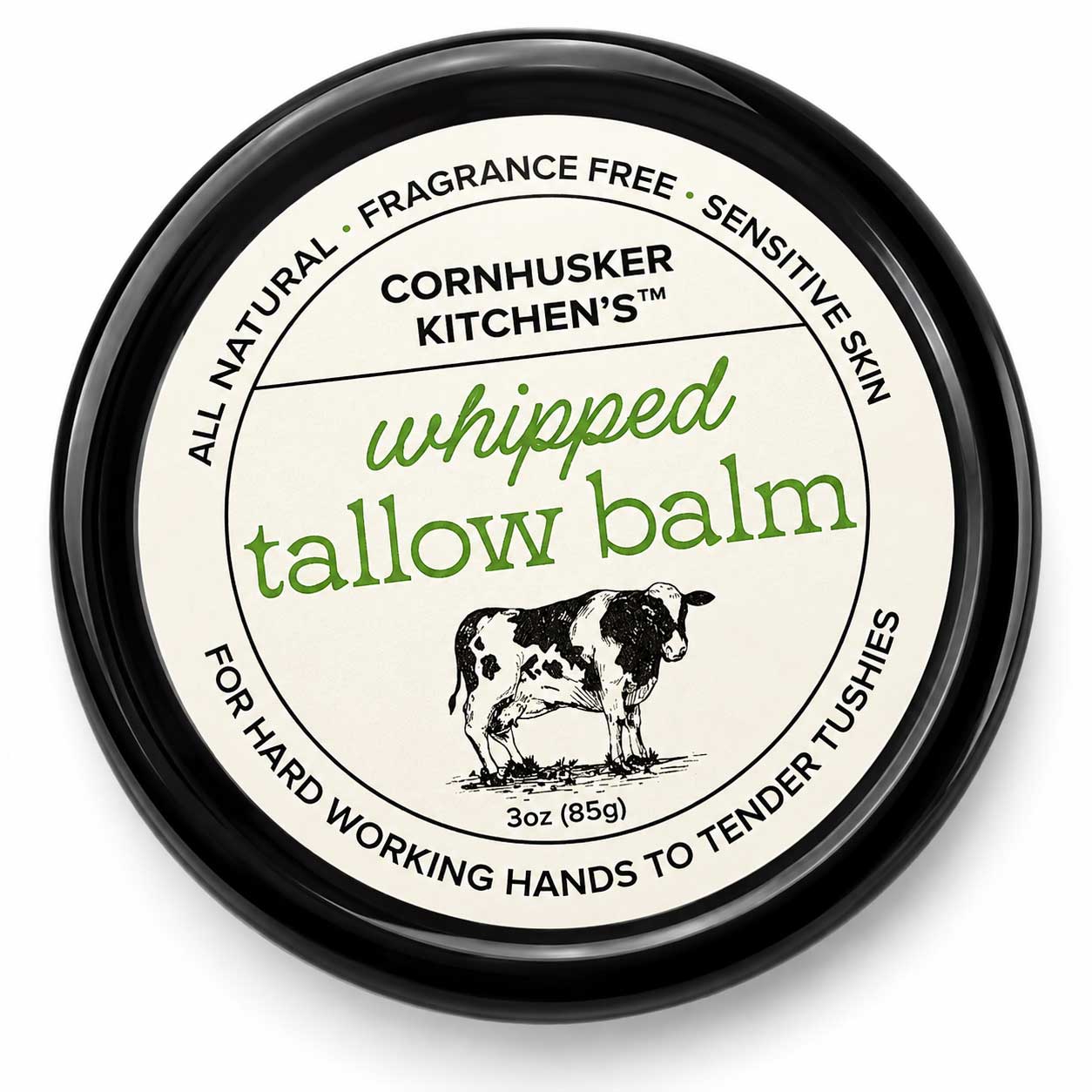 A round black tin of Cornhusker Kitchen's Whipped Tallow Balm, featuring a cream-colored label with green and black text and an illustration of a cow.