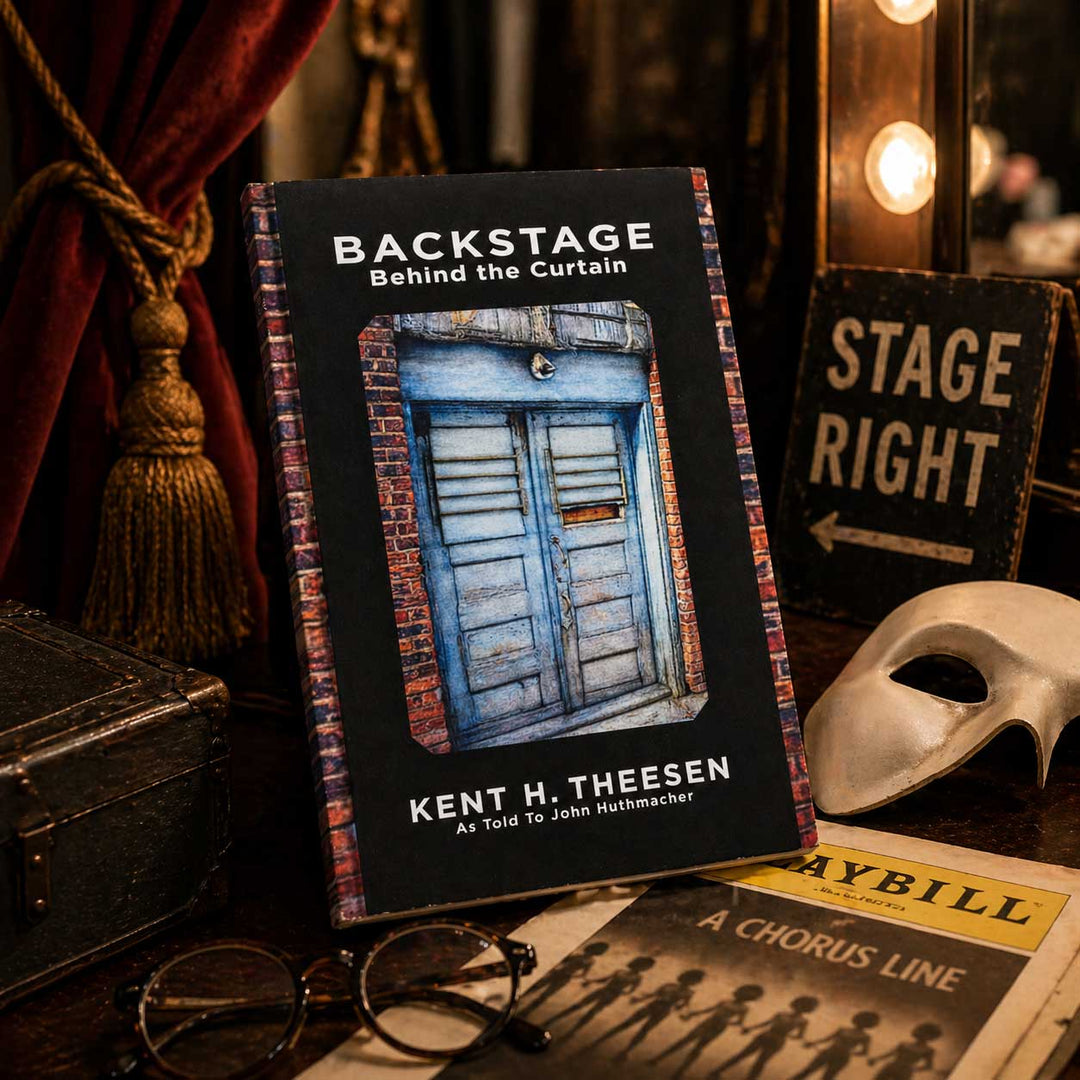 Book titled 'Backstage Behind the Curtain' by Kent H. Theesen with theater props in the background.