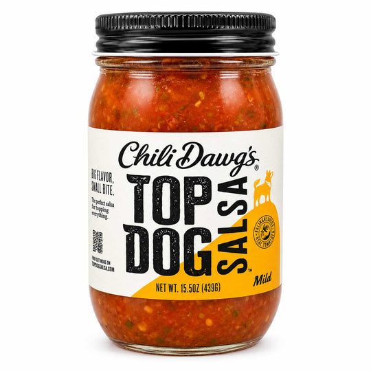 A jar of Chili Dawg's Top Dog Salsa, Mild, featuring a clear glass jar filled with chunky red-orange salsa, a white and yellow label, and a black metal lid, set against a plain white background.