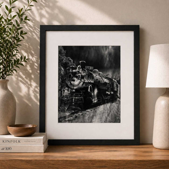 Framed black and white print of a steam locomotive on a wooden shelf with decorative items.
