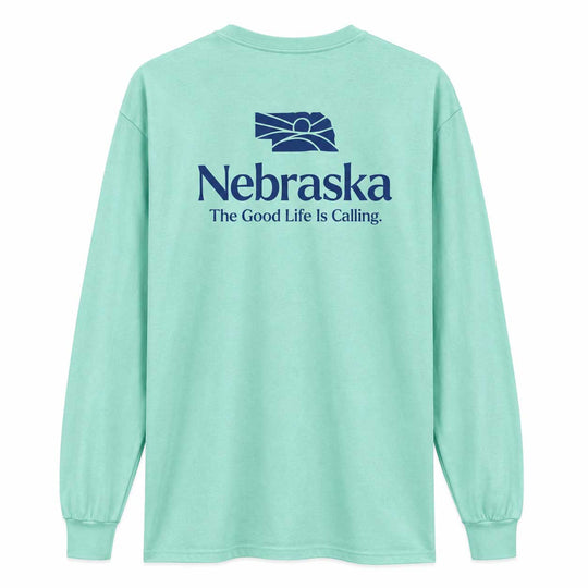A mint green long-sleeve t-shirt shown from the back, featuring a dark blue graphic of the Nebraska state silhouette with a rising sun and the text 'Nebraska The Good Life Is Calling.' printed on the back.