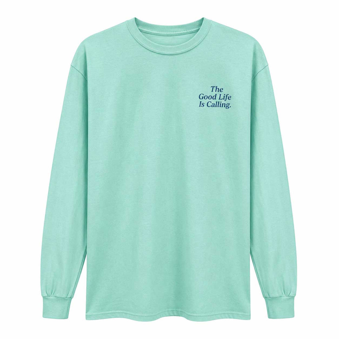 A mint green long-sleeve t-shirt with the text 'The Good Life Is Calling.' printed in dark blue on the left chest, displayed on a clean white background.