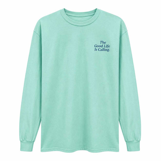 A mint green long-sleeve t-shirt with the text 'The Good Life Is Calling.' printed in dark blue on the left chest, displayed on a clean white background.