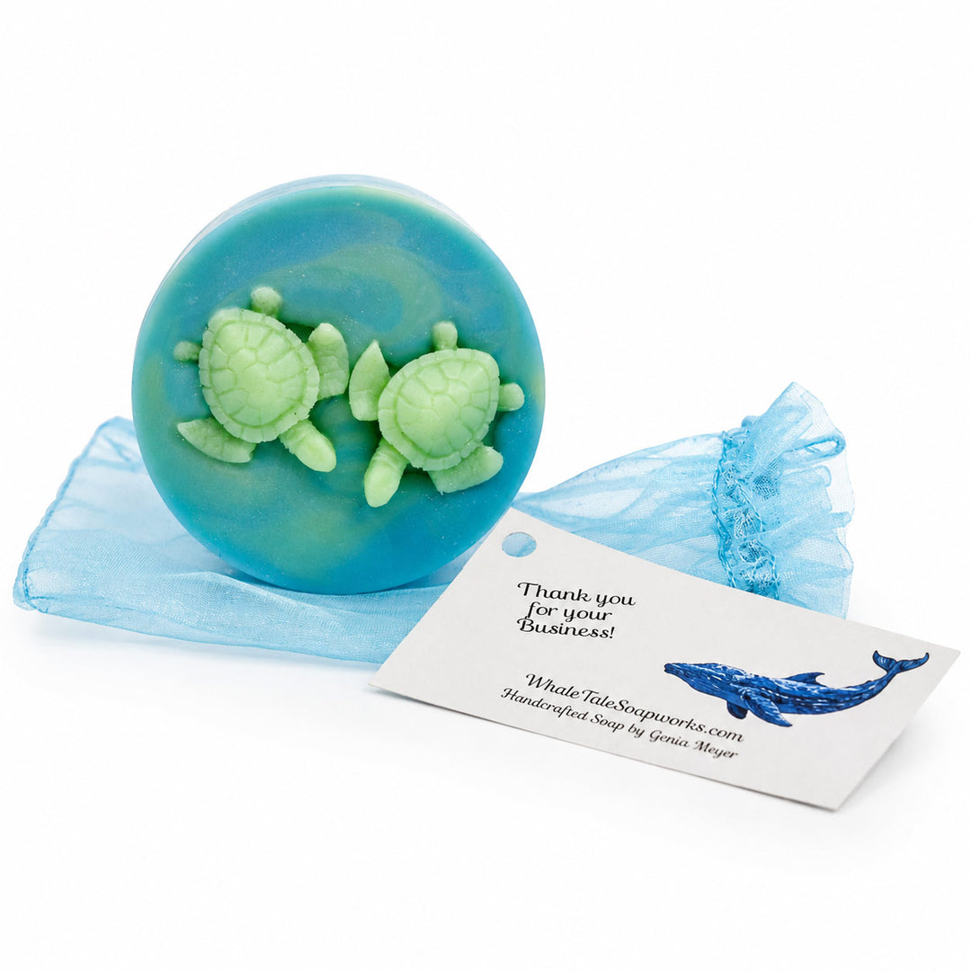 Blue soap with green turtle figures on a white background, featuring a business card from Whale Tale Soapworks.