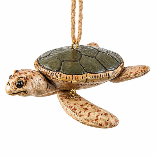 A sea turtle hanging ornament with a textured tan and brown shell and head, a darker olive-green shell, and a natural jute hanging loop at the top, shown against a plain white background.