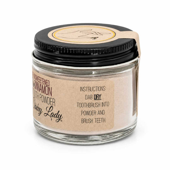 Glass jar of tooth powder with a black lid and brown label on a white background