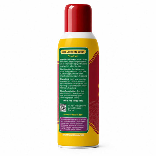 A yellow and red canister of Cornhusker Kitchen seasoning spray shown from the back, displaying detailed product instructions on a white background.