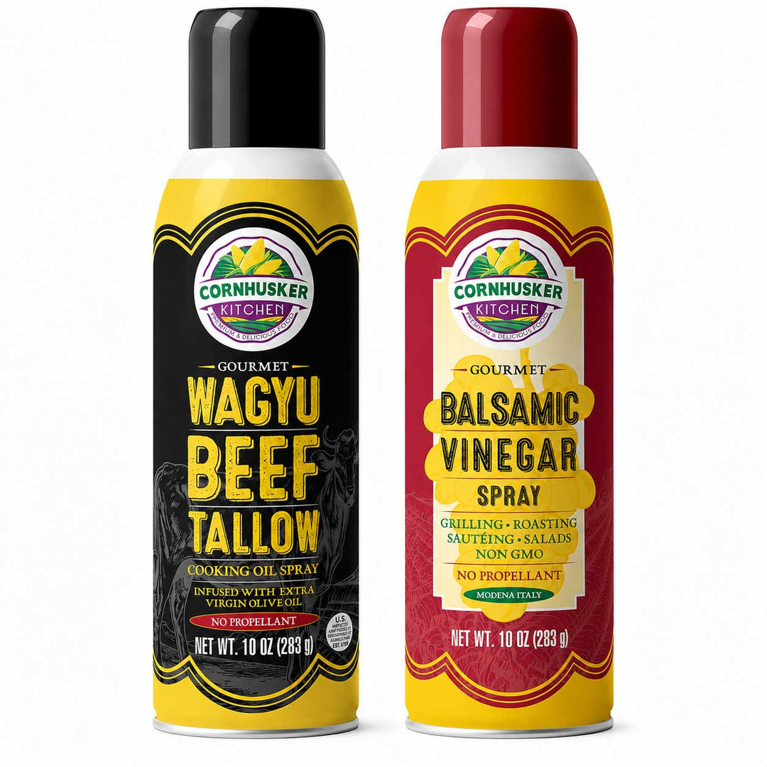 Two Cornhusker Kitchen spray cans on a white background: Wagyu Beef Tallow cooking oil spray with a black label and yellow can, and Balsamic Vinegar Spray with a red label and yellow can.