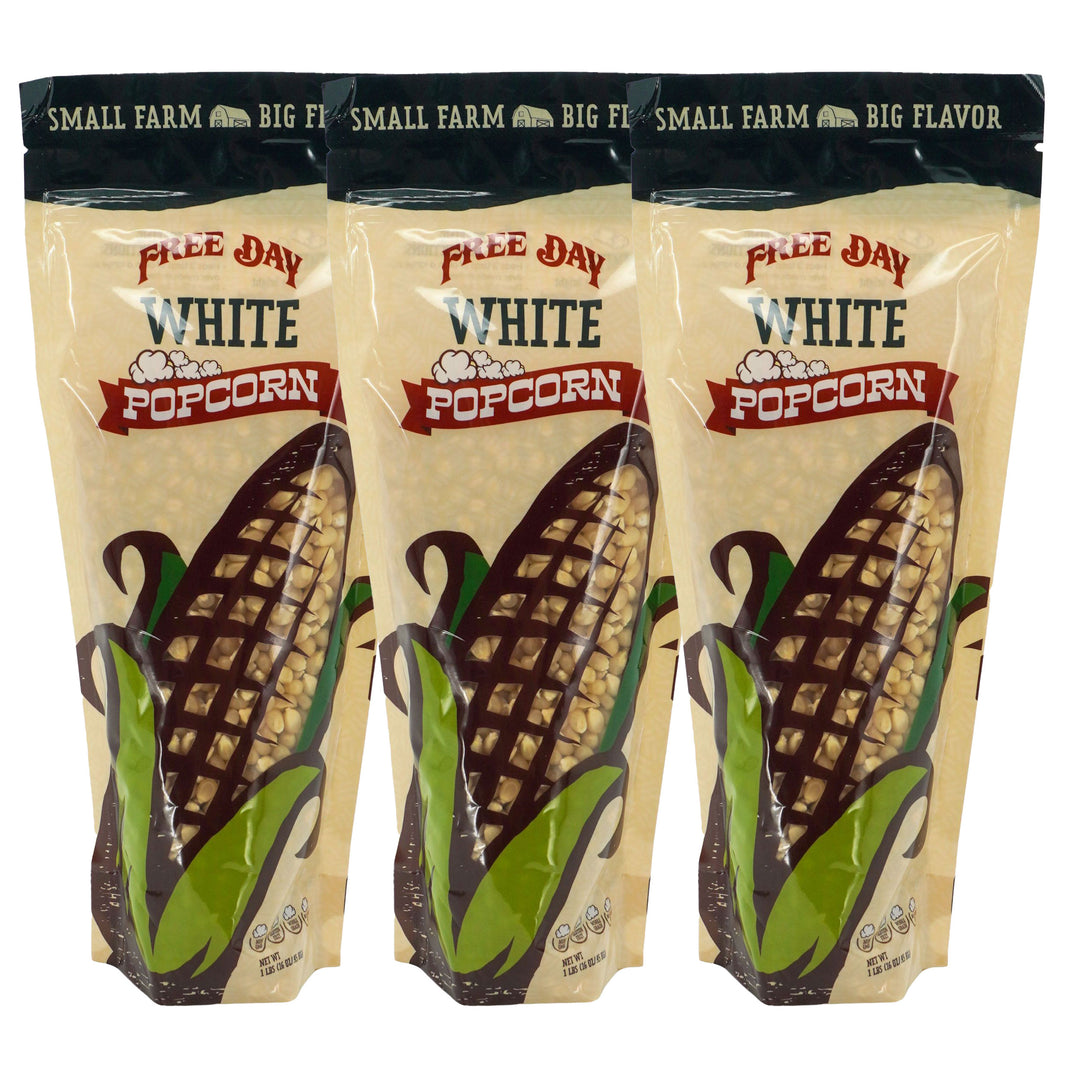 Three packages of Free Day White Popcorn with corn illustrations on a beige background.