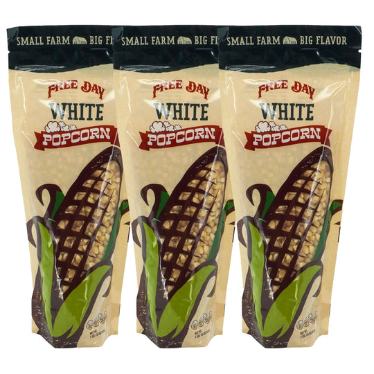 Three packages of Free Day White Popcorn with corn illustrations on a beige background.