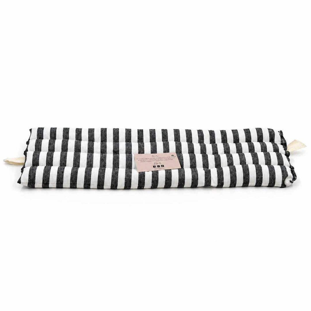 Black and white striped pillow with a pink label on a white background