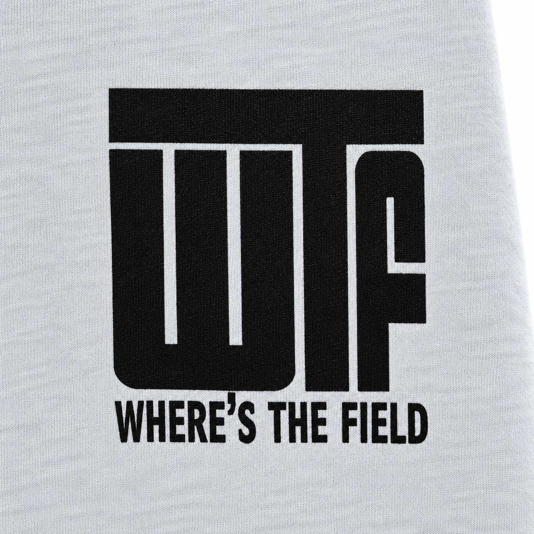 Close-up of a white heathered fabric surface with a large black printed graphic reading 'WTF' and smaller text 'WHERE'S THE FIELD' underneath.