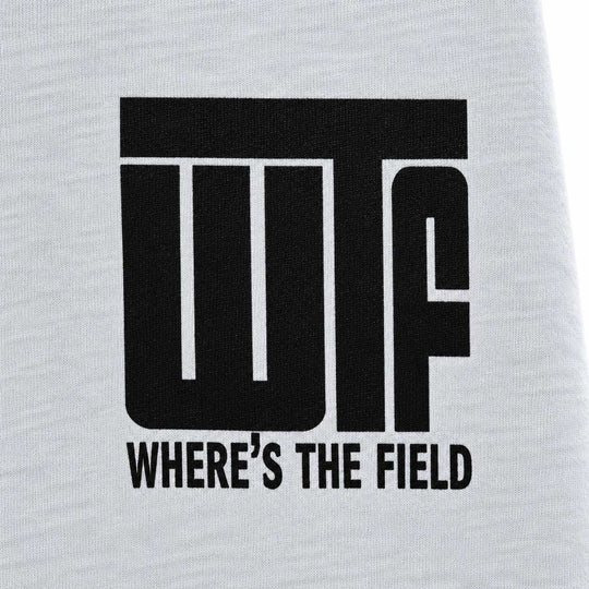 Close-up of a white heathered fabric surface with a large black printed graphic reading 'WTF' and smaller text 'WHERE'S THE FIELD' underneath.