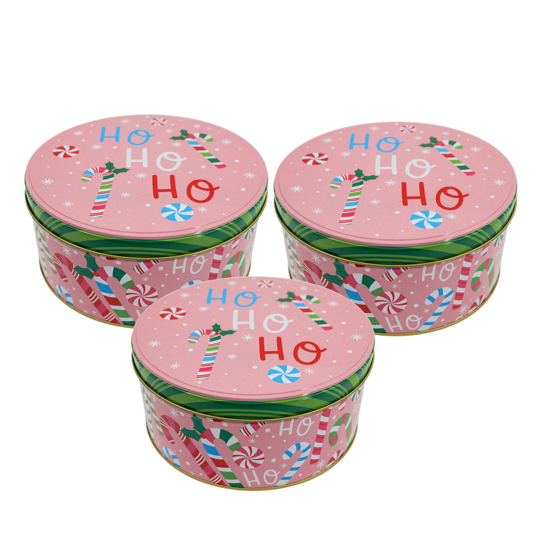 Three pink Christmas-themed tins with candy cane designs and 'HO HO HO' text on a white background.