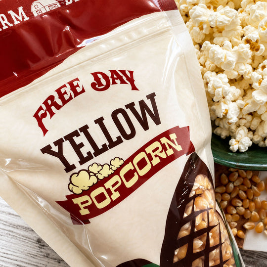 Bag of 'Free Day Yellow Popcorn' with popcorn and kernels on a wooden surface