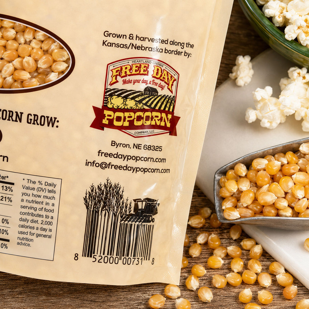Free Day Popcorn packaging with popcorn kernels and a bowl of popcorn on a wooden surface.