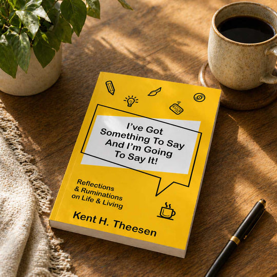 Book titled 'I've Got Something To Say And I'm Going To Say It!' by Kent H. Theesen on a wooden table with a cup of coffee and pen.