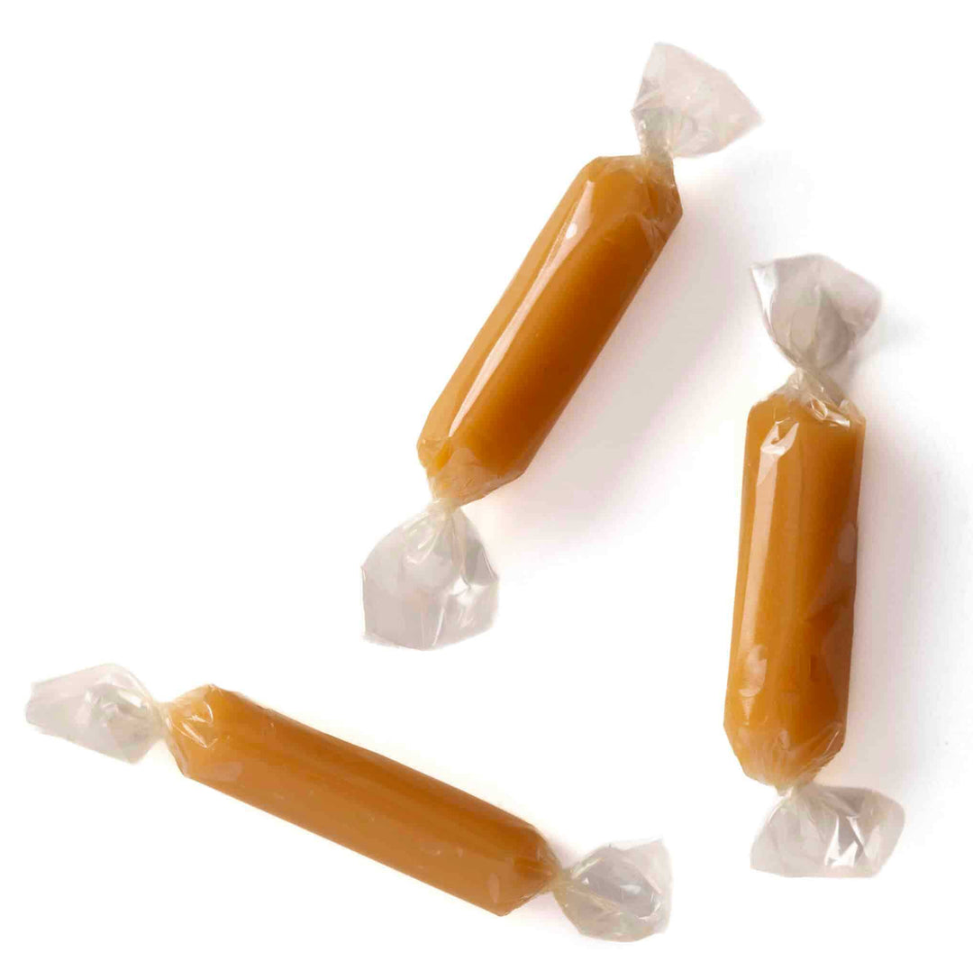 Three wrapped caramels on a white background