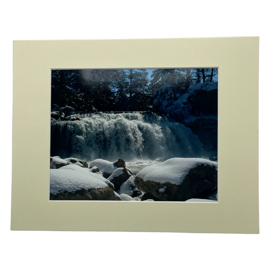 Photograph Of A Waterfall Behind Large, Snow-Covered Rocks With A Cream Colored Border