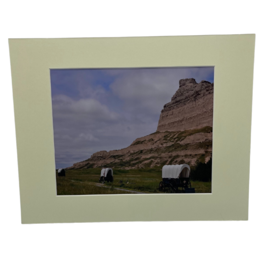 Image Of Three Covered Wagons Passing By A Large Cliff On The Oregon Trail