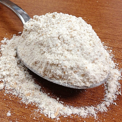 Spoonful Of Organic Spelt Flour Resting On A Brown Wooden Table 