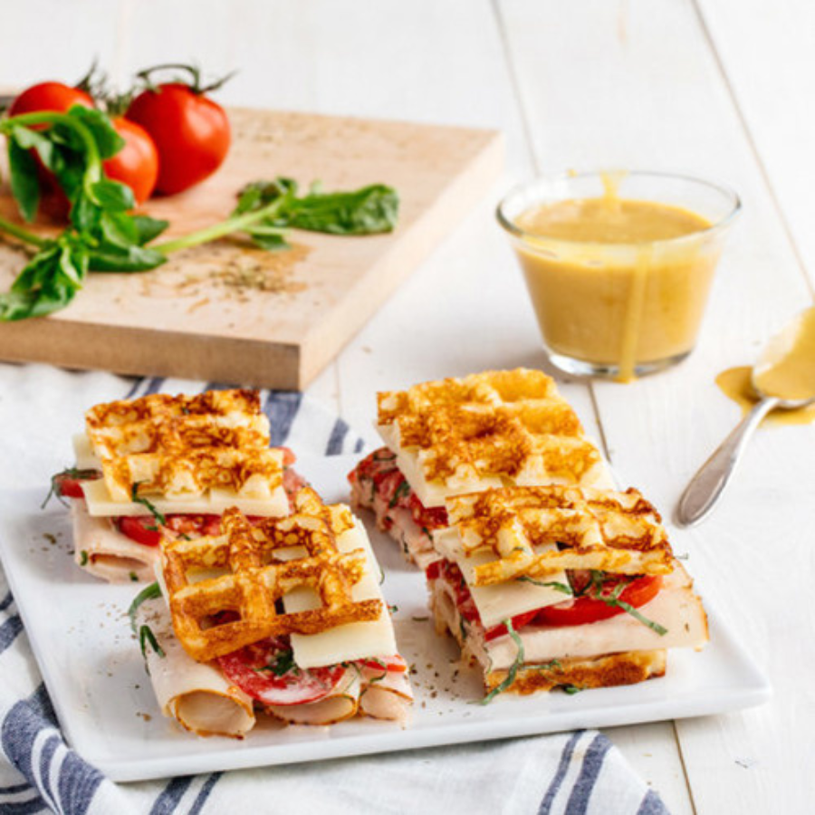 Plate of waffle sandwiches with turkey, cheese, and tomatoes.