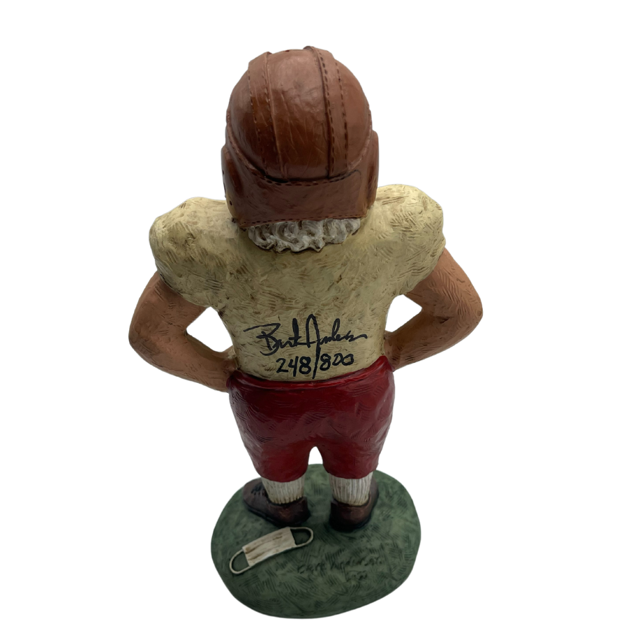 Back view of Santa wearing retro Husker football uniform with artist, Bert Anderson, signature on back with number 248/800. Covid facemask laying at feet and shown on a awhite background